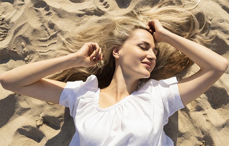 Femme blonde allongée sur le sable